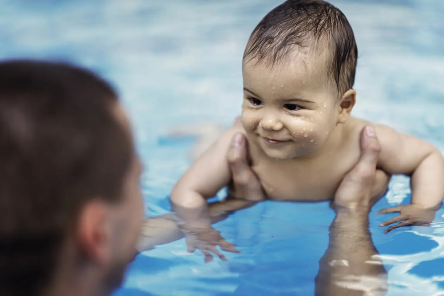 Infant in swimming pool with parent