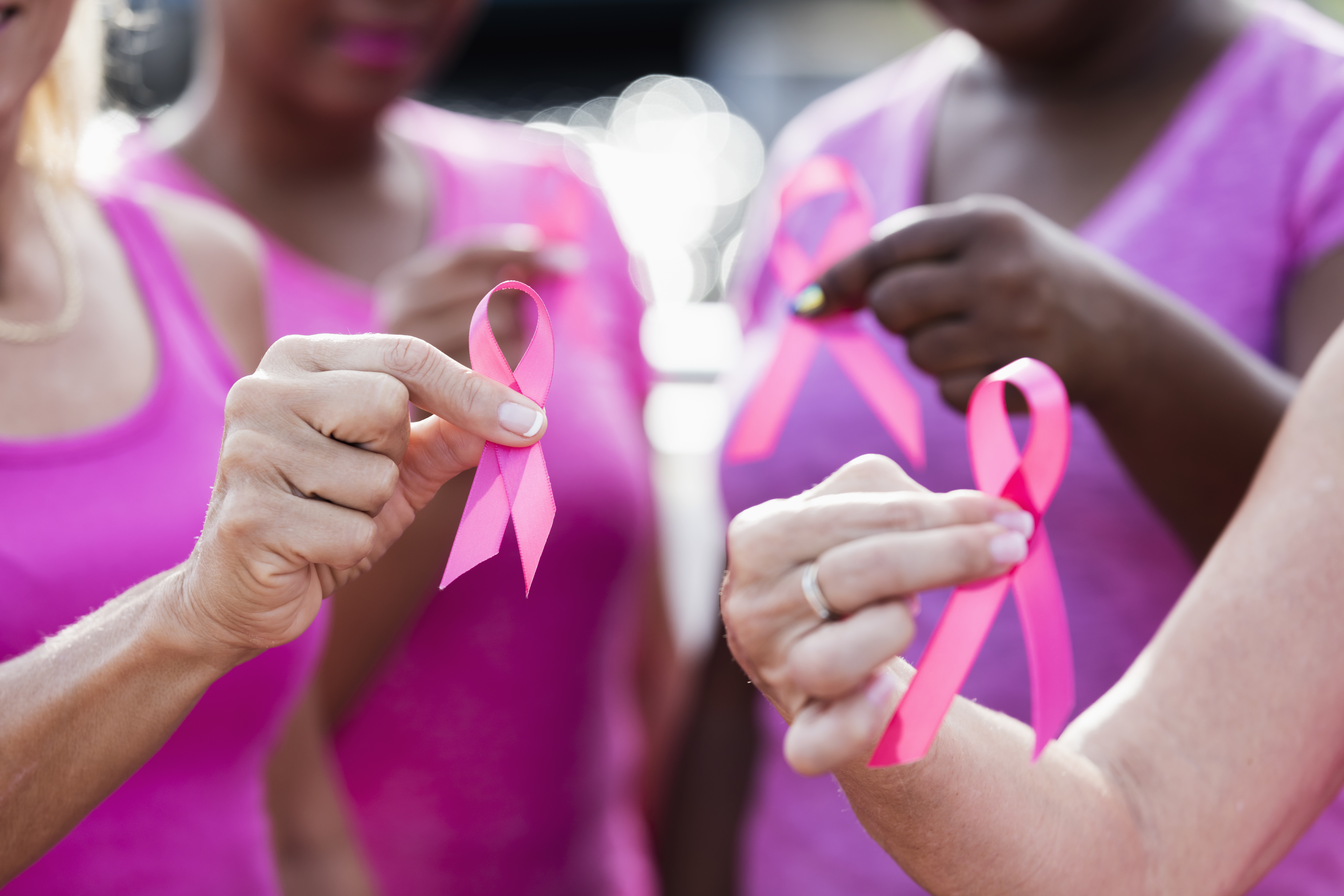 Hands holding pink ribbons